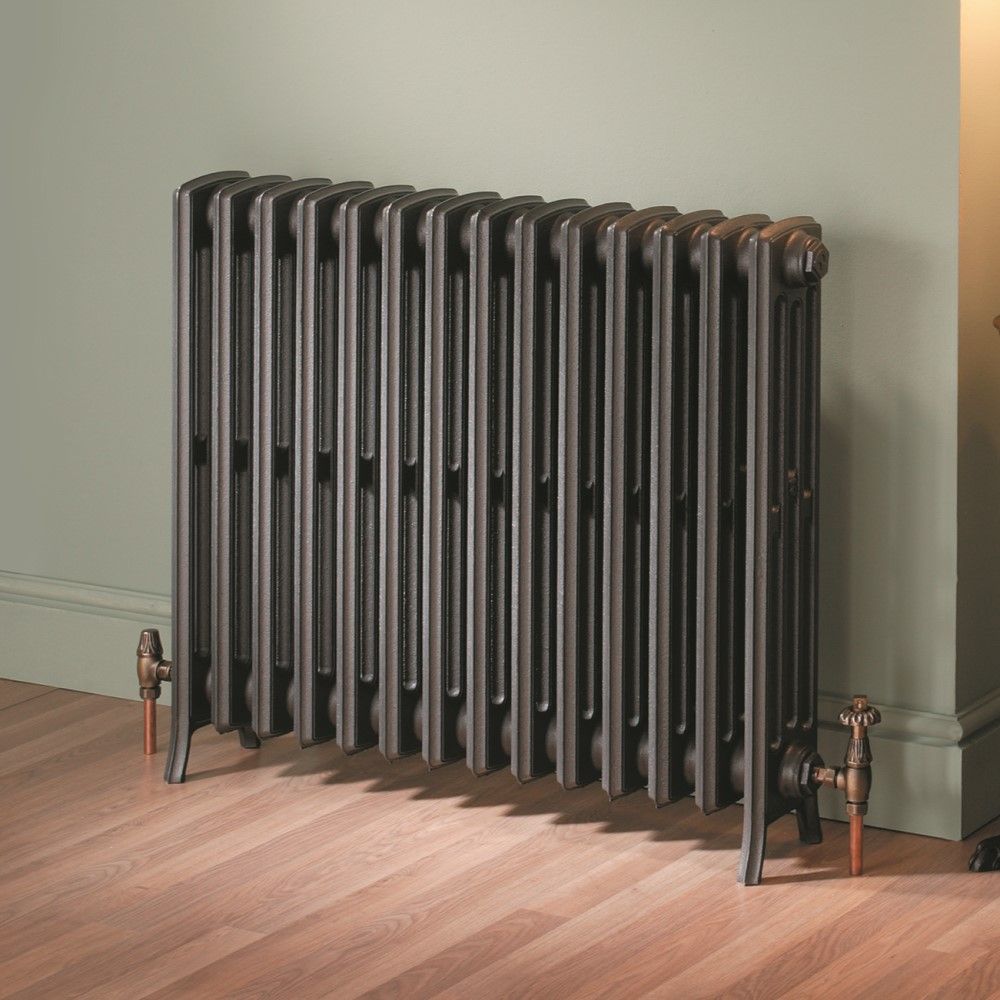 Black cast iron radiator with exposed copper pipes in a traditional interior setting.