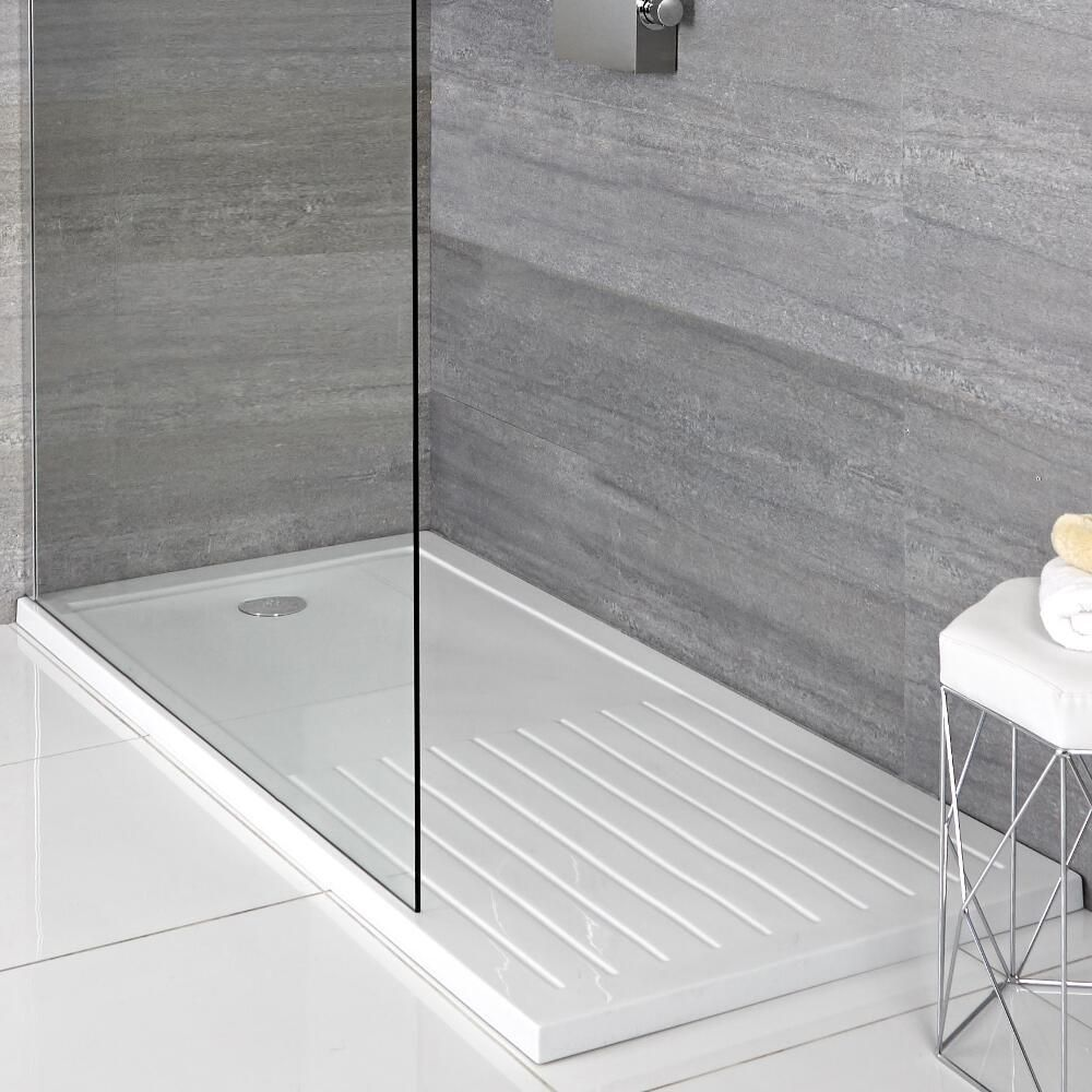 Glass shower with grey tiled wall, white walk-in shower tray, and stool holding white towels