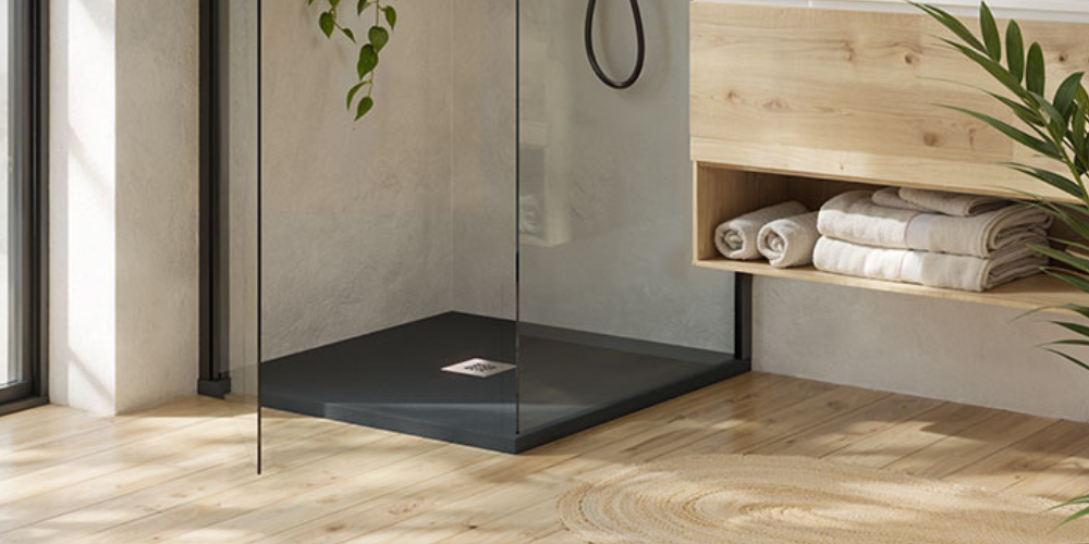 Minimalist bathroom with black square shower tray, glass screen, wooden cabinet, rolled towels, plants, and wooden floor