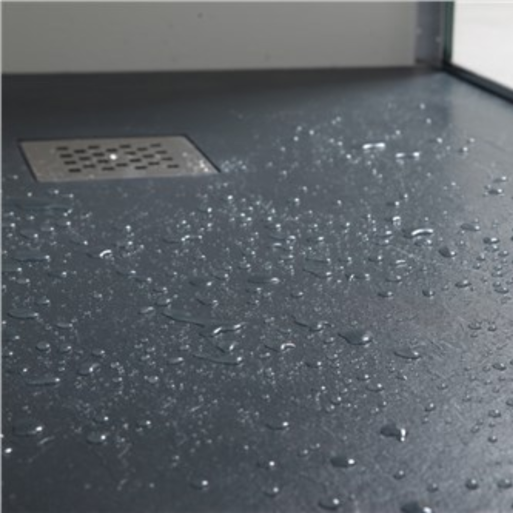 Dark stone resin shower tray with water droplets and metal drain, conveying freshness and clean surface