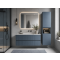 Blue bathroom vanity with illuminated mirror, wall-mounted storage cabinet, pendant lighting, and glass shower enclosure.