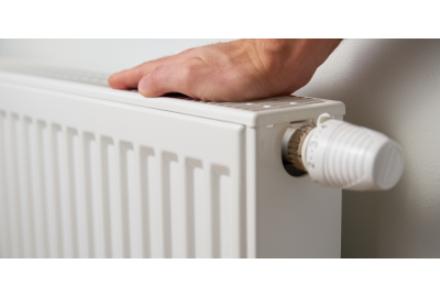 Hand touching the top of a white radiator