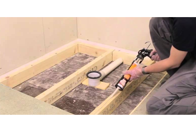 Worker applying adhesive to assemble new shower tray for bathroom